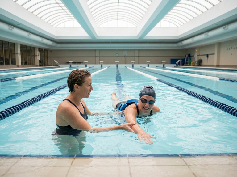 Monitrice guidant une nageuse debutante en piscine